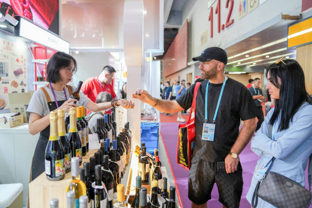 DIM点店饮食集团有限公司展位前，工作人员向客户介绍葡萄牙进口红酒。  南方+ 钟志辉 拍摄